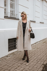 a lady in a black sequin velvet dress and a long beige overcoat